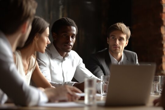 Diverse group of young professionals engaged in a serious discussion during a meeting.