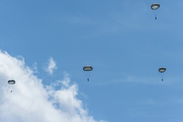 Army Paratroopers leap from a helicopter during a military training exercise, showcasing airborne deployment skills