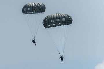 Army Paratroopers leap from a helicopter during a military training exercise, showcasing airborne deployment skills