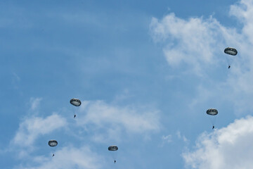 Army Paratroopers leap from a helicopter during a military training exercise, showcasing airborne deployment skills