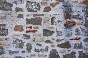 Weathered stone and brick wall with white plaster remnants
