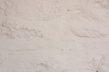 White plastered stone wall with rough uneven texture

