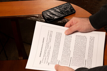 Naklejka premium Reviewing distributor contract agreement with smartphone on table 