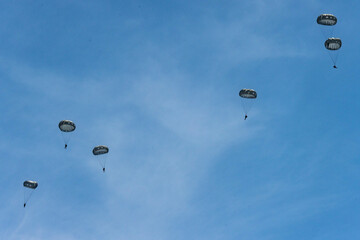 Army Paratroopers leap from a helicopter during a military training exercise, showcasing airborne deployment skills