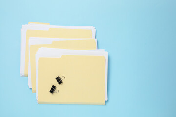 File folders with papers and binder clips on light blue background, flat lay. Space for text