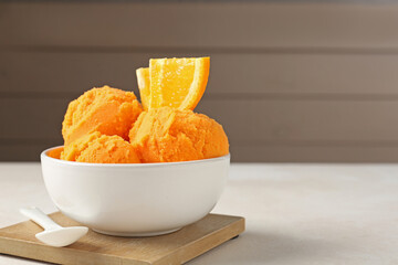Tasty orange sorbet, fresh fruit and spoon on light table, closeup. Space for text
