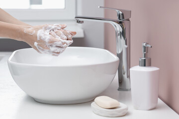 Woman washing hands at sink in bathroom, closeup
