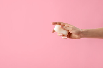 Woman with soap bar on light pink background, closeup. Space for text