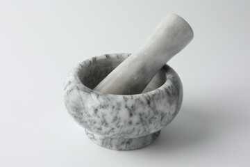 Marble mortar with pestle on white background, closeup