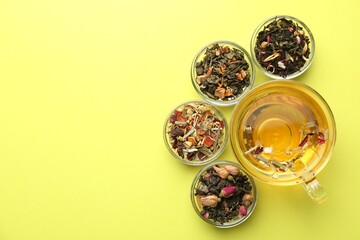 Delicious herbal tea in glass cup and dry leaves on green background, flat lay. Space for text