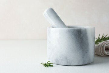 Marble mortar with rosemary and pestle on white table, closeup. Space for text