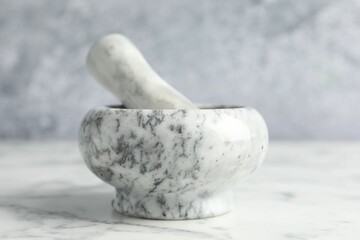 Mortar and pestle on white marble table, closeup