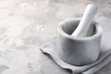 Marble mortar, pestle and cloth on grey textured table, closeup. Space for text