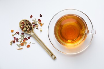 Delicious herbal tea and dry leaves on white background, top view
