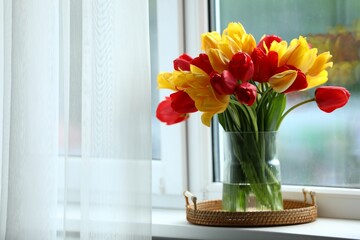 Beautiful tulips in vase on window sill