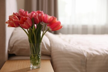 Bouquet of beautiful tulips on side table in bedroom. Space for text © New Africa