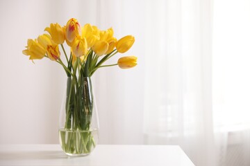 Bouquet of beautiful tulips on table near white wall. Space for text