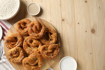 Tasty pretzels and ingredients on wooden table, flat lay. Space for text