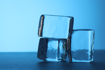 Cubes of clear ice on light blue background, closeup