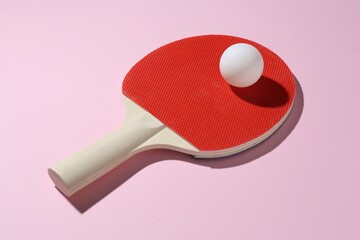 Ping pong racket and ball on pink background, closeup