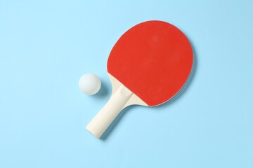 Ping pong racket and ball on light blue background, flat lay