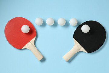 Ping pong rackets and balls on light blue background, flat lay