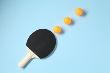 Ping pong racket and balls on light blue background, flat lay