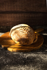 sourdough bread on a wooden cutting board at a stone table in soft sunlight with wooden background