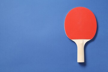 One ping pong racket on blue background, top view. Space for text