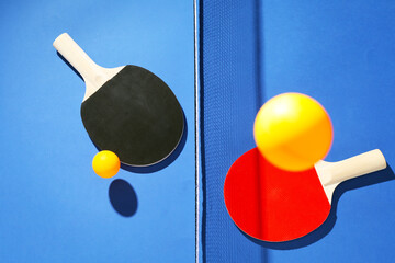 Ping pong rackets, balls and net on blue background, flat lay