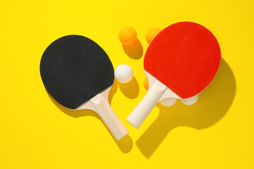 Ping pong rackets and balls on yellow background, flat lay