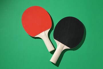 Ping pong rackets on green background, top view