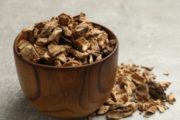 Pieces of dry chicory roots in bowl on gray table, closeup
