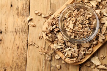 Pieces of dry chicory roots in bowl on wooden table, top view. Space for text