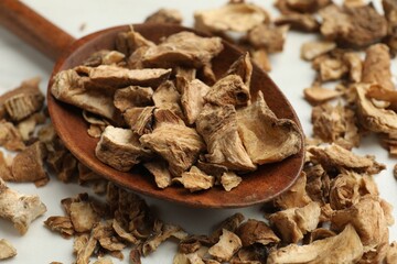 Pieces of dry chicory roots in spoon on white table, closeup