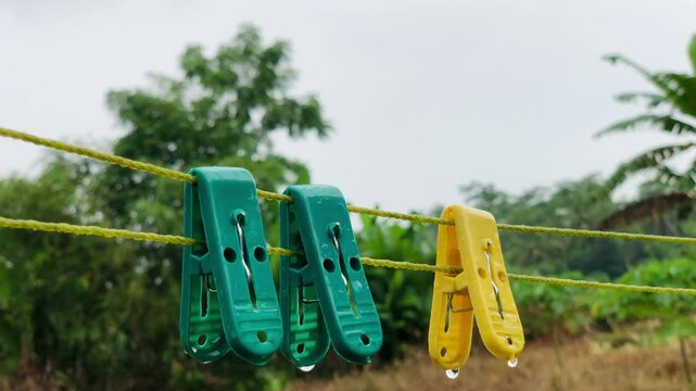 footage of colorful clothes pegs being drenched by rain
