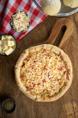 pizza  con queso en fondo de madera con luz lateral toma cenital