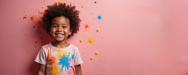 Cheerful african american child with stained t-shirt smiles. Pink background with colorful paint splashes. Playful art project. Creative childhood. Empty space for text copy paste. Art school, hobby.