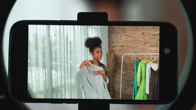 Rear view behide smartphone screen recording woman influencer shoot live stream vlog video review clothe crucial social media or blog. Girl with apparel studio lighting for marketing broadcast online
