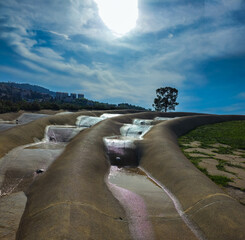 The photo depicts an installation in the form of a slide made of stone in the shape of a wave with...