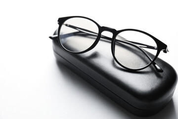 Case with stylish glasses on light background, closeup