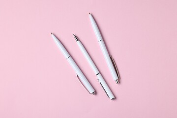 Ballpoint pens on pink background, flat lay
