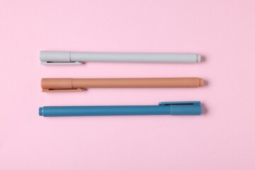 Stylish pens on pink background, flat lay