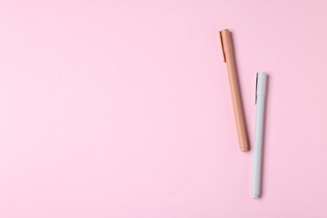 Stylish pens on pink background, top view. Space for text