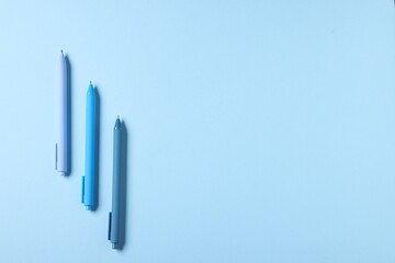 Stylish pens on light blue background, flat lay. Space for text