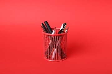 Ballpoint pens in holder on red background