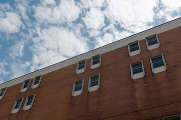 Red brick building under a blue sky with white clouds during the bright daylight hours