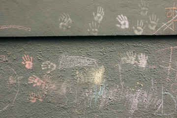 Colorful handprints and chalk drawings on a weathered wall in an urban playground celebrating creativity and joy
