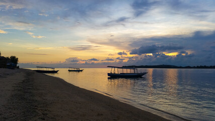 Obraz premium beautiful dramatic landscape of sunset on sea beach with silhouette of boat