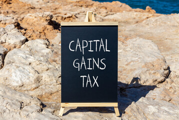 Capital gains tax symbol. Concept words Capital gains tax on beautiful blackboard. Beautiful brown...